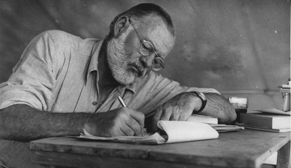 Ernest_Hemingway_Writing_at_Campsite_in_Kenya_-_NARA_-_192655